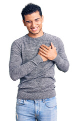 Sticker - Hispanic handsome young man wearing casual sweater smiling with hands on chest with closed eyes and grateful gesture on face. health concept.