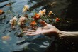 © Kishore Newton - A hand gently touching water surface, with delicate flowers floating around, conveying a sense of calm and introspection.