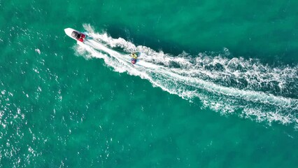 Wall Mural - Aerial drone video of extreme inflatable towable tube cruising in high speed attached on powerboat with children riding, watersport