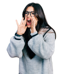 Poster - Beautiful hispanic woman wearing casual sweater and glasses shouting angry out loud with hands over mouth