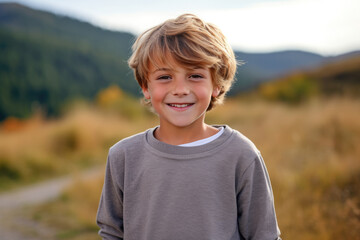 Wall Mural - A young boy wearing a grey sweater smiles for the camera