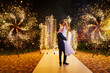 © andrey - The bride and groom on the wedding ceremony venue with fireworks at night .