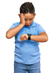 Sticker - Little boy hispanic kid wearing casual clothes looking at the watch time worried, afraid of getting late