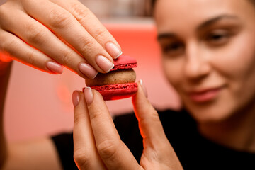 Wall Mural - Confectioner holds two halves of red macaroon with beige cream together, close up