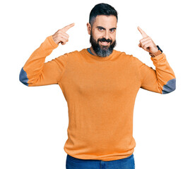 Wall Mural - Hispanic man with beard wearing casual winter sweater smiling pointing to head with both hands finger, great idea or thought, good memory