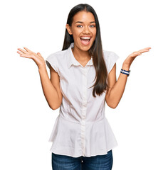 Canvas Print - Beautiful hispanic woman wearing casual clothes celebrating victory with happy smile and winner expression with raised hands