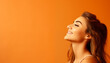© EVF Images - Mujer joven con cabello castaño sonriendo sobre fondo naranja. Espacio para texto.