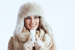 © Alliance - happy stylish woman in winter coat and fur hat on white