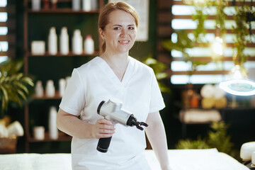 Poster - happy female massage therapist in spa salon with massage pistol