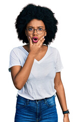 Poster - Young african american woman wearing casual white t shirt looking fascinated with disbelief, surprise and amazed expression with hands on chin