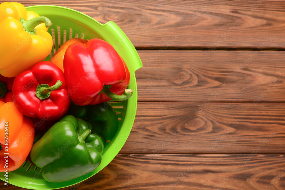 Colander with fresh peppers on wooden background