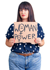 Canvas Print - Young plus size woman holding woman power banner thinking attitude and sober expression looking self confident