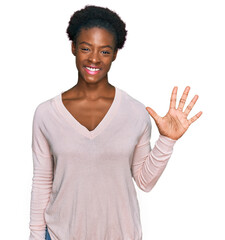 Wall Mural - Young african american girl wearing casual clothes showing and pointing up with fingers number five while smiling confident and happy.