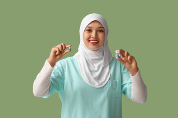 Sticker - Female Muslim doctor in hijab with pills on green background. World Hijab Day concept