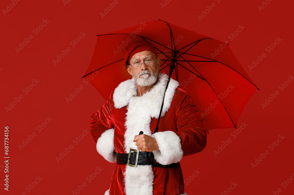 Santa Claus in glasses with umbrella on red background