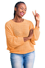 Sticker - Young african american woman wearing casual clothes smiling with happy face winking at the camera doing victory sign. number two.