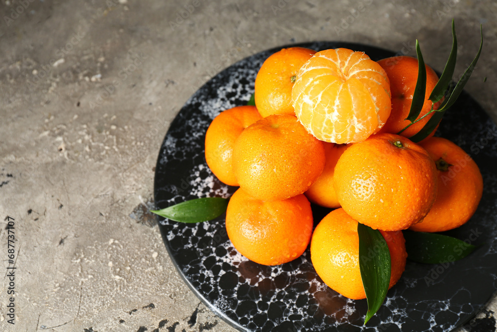 Board with sweet mandarins and leaves on grey table