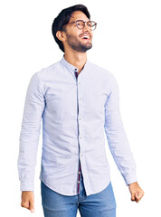 Poster - Handsome hispanic man wearing business shirt and glasses looking away to side with smile on face, natural expression. laughing confident.