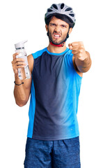 Poster - Handsome hispanic man wearing bike helmet and holding water bottle annoyed and frustrated shouting with anger, yelling crazy with anger and hand raised