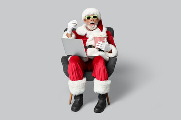 Sticker - Santa Claus in 3D glasses with bucket of tasty popcorn and laptop watching movie on grey background