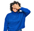 © Krakenimages.com - Young hispanic woman with curly hair wearing turtleneck sweater smiling and laughing with hand on face covering eyes for surprise. blind concept.