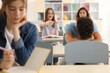 © New Africa - Teen problems. Lonely boy sitting separately from other students in classroom