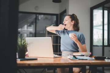 Bored businesswoman yawning at workplace feeling no motivation or lack of sleep tired of boring office routine.