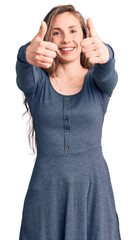 Sticker - Young beautiful blonde woman wearing casual dress approving doing positive gesture with hand, thumbs up smiling and happy for success. winner gesture.