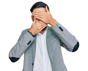 Wall Mural - Young hispanic man wearing business clothes covering eyes and mouth with hands, surprised and shocked. hiding emotion