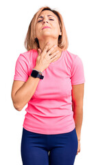 Wall Mural - Young blonde woman wearing sportswear touching painful neck, sore throat for flu, clod and infection