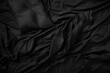 Top view of an unmade black bed with a crumpled sheet and pillows in the morning