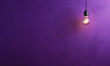 arrière plan violet uni avec une ampoule allumée qui pend