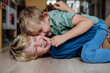 Two little boys fighting on the floor, brothers having fun at home. Concept of sibling relationship and brotherly love.