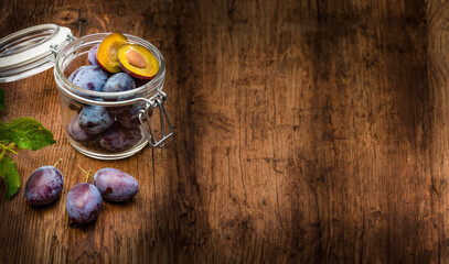 Wall Mural - plums in a bottle on a wooden table