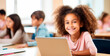 © MYDAYcontent - African American girl seated at table, utilizing laptop for online lesson