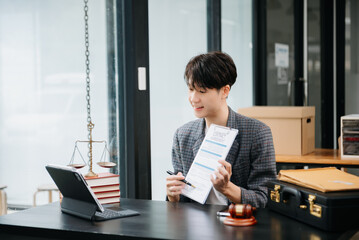 Asian female lawyer chatting online with client on laptop, smartphone  discussing details of lawsuit. in modern office..