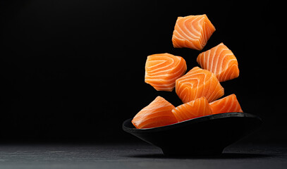 Falling salmon cubes on black background