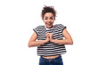 © Ivan Traimak - young happy curly brunette lady with black hair dressed in a striped t-shirt rejoices on a white background. people emotions concept