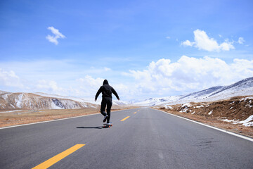 Wall Mural - Skateboarder skateboarding on snowy country road