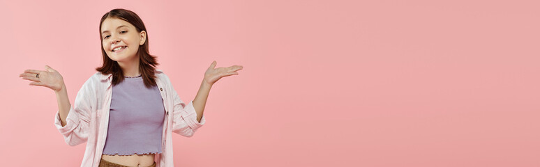 Wall Mural - happy teenage girl in casual attire posing with open arms and looking at camera on pink, banner