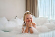© Westend61 - Blond girl covering mouth and laughing in bathtub