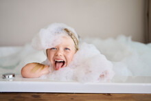 Playful Girl Covered In Soap Suds And Sticking Out Tongue