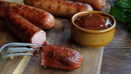 Wall Mural - Grilled sausages Bockwurst on a wooden board. Break and pricked sausage with a fork. Close up