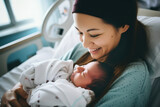 Fototapeta  - Beautiful young mother holding her newborn in maternity ward after delivery. New mom welcoming her first child into the world. Woman after labor in hospital bed.