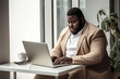 © Наталья Лазарева - fat black man ,plus-size, manager, in beige business clothes sitting at a desk with a laptop in a modern office, the concept of diversity