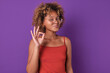 Young beautiful confident African American woman student with glasses shows confirming gesture saying that everything is ok or agreeing to your commercial proposal stands posing on purple background.