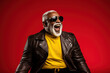 Crazy cool hipster African American gray haired senior man pretending being rocker having fun isolated on red background. Funny funky ethnic old generation fashion model screaming singing.