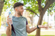 Young handsome sport man with a bottle of water at outdoors with surprise facial expression