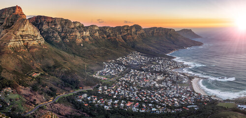 Wall Mural - cape town aerial panorama from the table mountain at sunset, sun shining on the mountain range town in the dusk