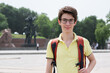 Young handsome 15 years old teen boy wearing yellow t-shirt with backpack looking at camera and happy smiling, summer park outdoor